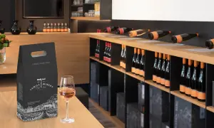 Una confezione regalo per una bottiglia di vino, con un calice di vino rosato in primo piano. Perfetto per sapere come regalare una bottiglia di vino.