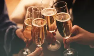 Brindisi con bollicine dorate. Mani che sollevano calici per un brindisi, un momento di gioia e celebrazione. Cin cin!