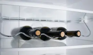 Bottiglie di vino bianco su un ripiano cromato all'interno di un frigorifero.