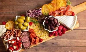 Un invitante tagliere di formaggi misti, salumi, olive, lamponi e crostini, perfetto per un aperitivo.