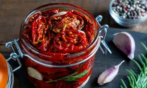 Pomodori secchi sott'olio in un barattolo, con aglio e rosmarino. Un sapore intenso che evoca l'umami, significato di gusto profondo.