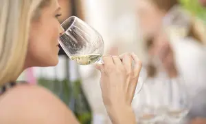 Donna bionda assapora un vino bianco, forse un vino 15 gradi, in un ambiente conviviale.