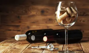 Calici pieni di tappi, bottiglie e cavatappi su un tavolo di legno. Un promemoria visivo dell'ossidazione del vino e del tempo che passa.