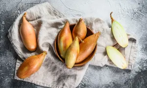 Scalogno cos'è? Cipolle allungate, dorate e verdi, alcune intere, altre tagliate a metà, su un panno di lino.