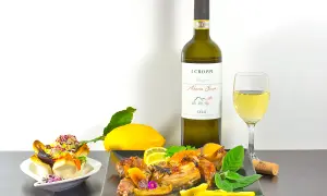 Piatto di coniglio arrosto con limone e erbe aromatiche, accompagnato da un bicchiere e una bottiglia di vino Albana Secco, perfetto vino da abbinare al coniglio.