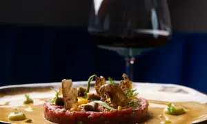 Tartare di manzo raffinata, guarnita con crostini e verdure, pronta per un perfetto abbinamento vino.