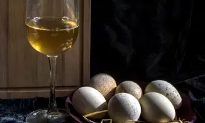 Un calice di vino dorato e un piatto di uova rustiche, un'idea su cosa abbinare alle uova per un pasto semplice e gustoso.