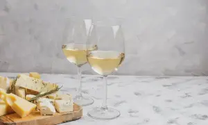 Due calici di vino bianco, perfetti per accompagnare un tagliere di formaggi misti, tra cui erborinato e stagionato.