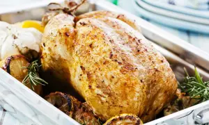 Pollo arrosto dorato, un esempio di carni bianche quali sono, con limone, aglio e rosmarino in una teglia.