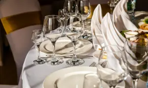 Tavola apparecchiata con bicchieri vuoti e tovaglioli piegati. Il galateo bottiglia di vino finita è rispettato, si attende il prossimo servizio.