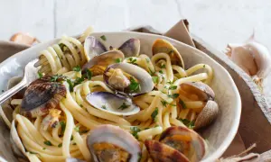 Un piatto invitante di spaghetti alle vongole, con pasta spessa e molluschi succulenti, guarnito con prezzemolo fresco.