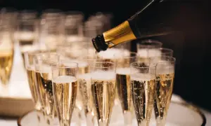 Bollicine dorate salgono in bicchieri di spumante, un brindisi che evoca il profumo millesimato significato di festa e celebrazione.