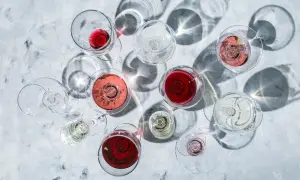 Vari calici di vino rosso, rosato e bianco, con ombre suggestive. La temperatura ideale per gustare un buon vino rosso è fondamentale.