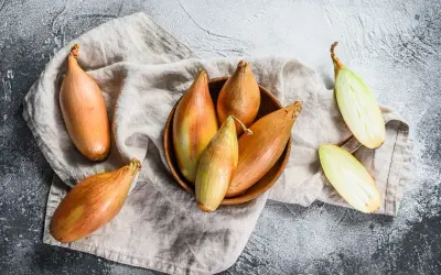 Scalogno cos'è? Cipolle allungate, dorate e verdi, alcune intere, altre tagliate a metà, su un panno di lino.