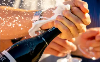 Le mani aprono una bottiglia di spumante, la schiuma esplode. La pressione della bottiglia spumante è alta, pronta per festeggiare.