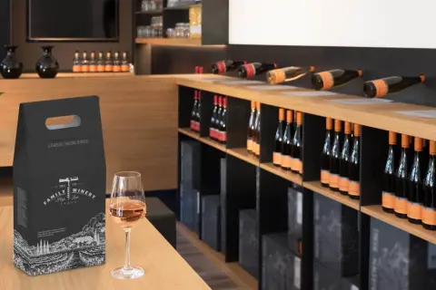 Una confezione regalo per una bottiglia di vino, con un calice di vino rosato in primo piano. Perfetto per sapere come regalare una bottiglia di vino.