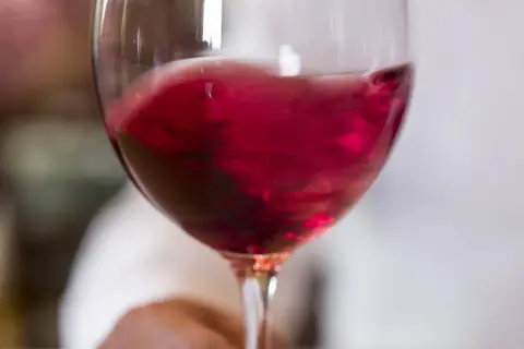Un bicchiere di vino rosso vibrante, quasi in movimento, pronto per essere raffreddato.