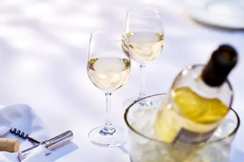 Due calici e una bottiglia di vino bianco in un secchiello di ghiaccio. Quanto tempo per il vino bianco in freezer? Meglio in frigo!