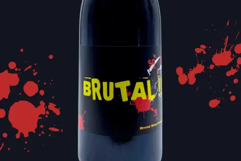 Bottiglia di vino "Brutal" con etichetta nera e gialla, macchie rosse che ricordano il sangue. Esistono vini senza solfiti, come questo.