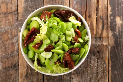 Insalata fresca con fave, pomodori secchi e lattuga. Le fave sono legumi nutrienti, perfetti per un piatto leggero e gustoso.