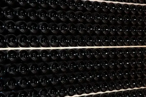 Fila di bottiglie scure, un'immagine che evoca il batonnage cos'è, la tecnica di agitazione per affinare il vino.