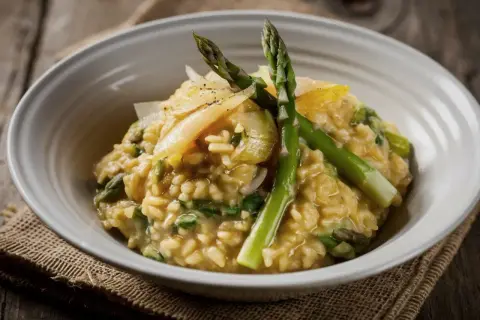 Risotto cremoso con asparagi freschi e scaglie di parmigiano. Un perfetto abbinamento asparagi per un piatto primaverile.