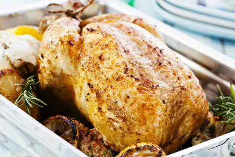 Pollo arrosto dorato, un esempio di carni bianche quali sono, con limone, aglio e rosmarino in una teglia.