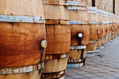 File di botti di legno in fila, pronte per la maturazione. La loro capacità barrique è fondamentale per il vino.