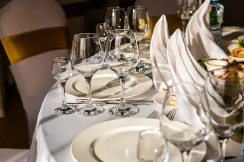 Tavola apparecchiata con bicchieri vuoti e tovaglioli piegati. Il galateo bottiglia di vino finita è rispettato, si attende il prossimo servizio.