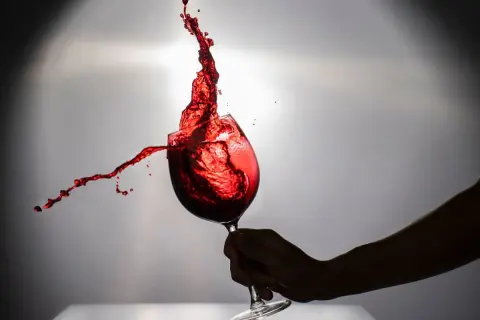 Un bicchiere di negramaro vino rosso in movimento, con schizzi vibranti che danzano nell'aria.