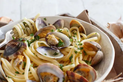 Un piatto invitante di spaghetti alle vongole, con pasta spessa e molluschi succulenti, guarnito con prezzemolo fresco.