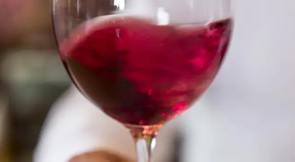 Un bicchiere di vino rosso vibrante, quasi in movimento, pronto per essere raffreddato.