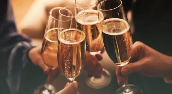 Brindisi con bollicine dorate. Mani che sollevano calici per un brindisi, un momento di gioia e celebrazione. Cin cin!