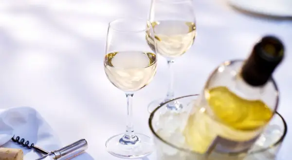 Due calici e una bottiglia di vino bianco in un secchiello di ghiaccio. Quanto tempo per il vino bianco in freezer? Meglio in frigo!