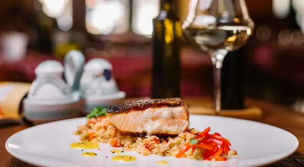 Salmone croccante su couscous con peperoni rossi. Un'idea perfetta su cosa abbinare al salmone, accompagnato da un bicchiere di vino bianco.