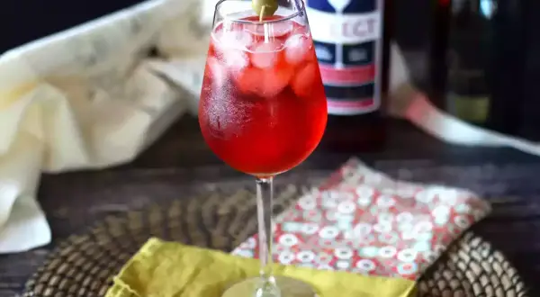 Un bicchiere di Spritz Select, con ghiaccio e oliva, pronto per essere gustato. La ricetta perfetta per un aperitivo rinfrescante.