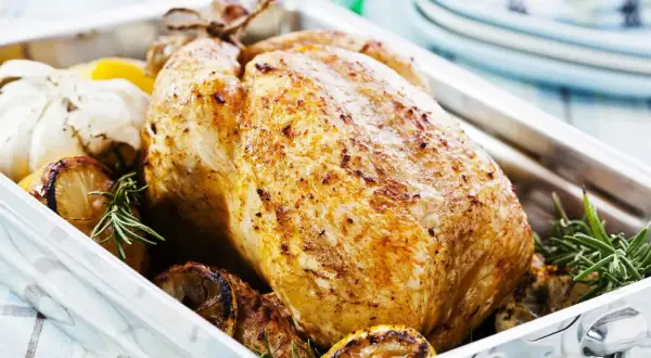 Pollo arrosto dorato, un esempio di carni bianche quali sono, con limone, aglio e rosmarino in una teglia.