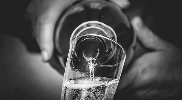 Versando bollicine in un bicchiere, un brindisi che evoca il metodo Charmat.