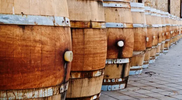 File di botti di legno in fila, pronte per la maturazione. La loro capacità barrique è fondamentale per il vino.