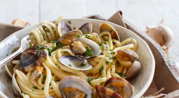 Un piatto invitante di spaghetti alle vongole, con pasta spessa e molluschi succulenti, guarnito con prezzemolo fresco.
