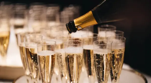 Bollicine dorate salgono in bicchieri di spumante, un brindisi che evoca il profumo millesimato significato di festa e celebrazione.