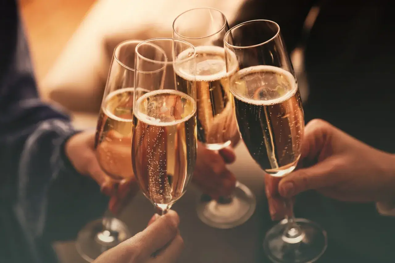 Brindisi con bollicine dorate. Mani che sollevano calici per un brindisi, un momento di gioia e celebrazione. Cin cin!
