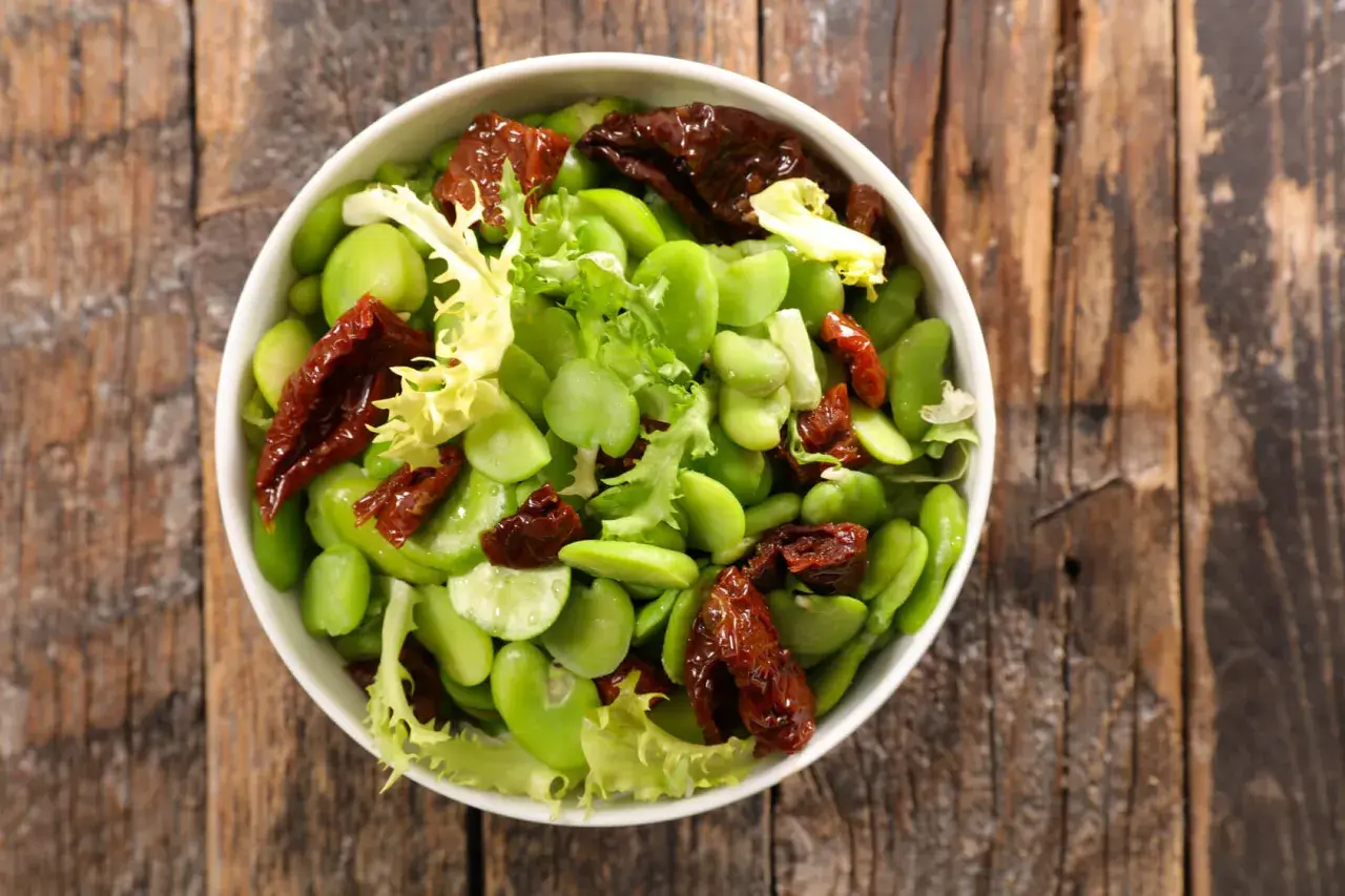 Insalata fresca con fave, pomodori secchi e lattuga. Le fave sono legumi nutrienti, perfetti per un piatto leggero e gustoso.