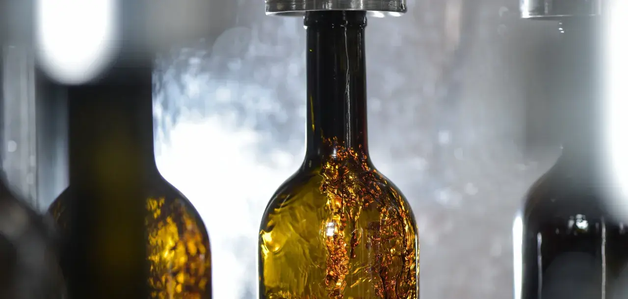 Bottiglie di vino ambrato in fase di imbottigliamento, un momento cruciale nel calendario per imbottigliare il vino.