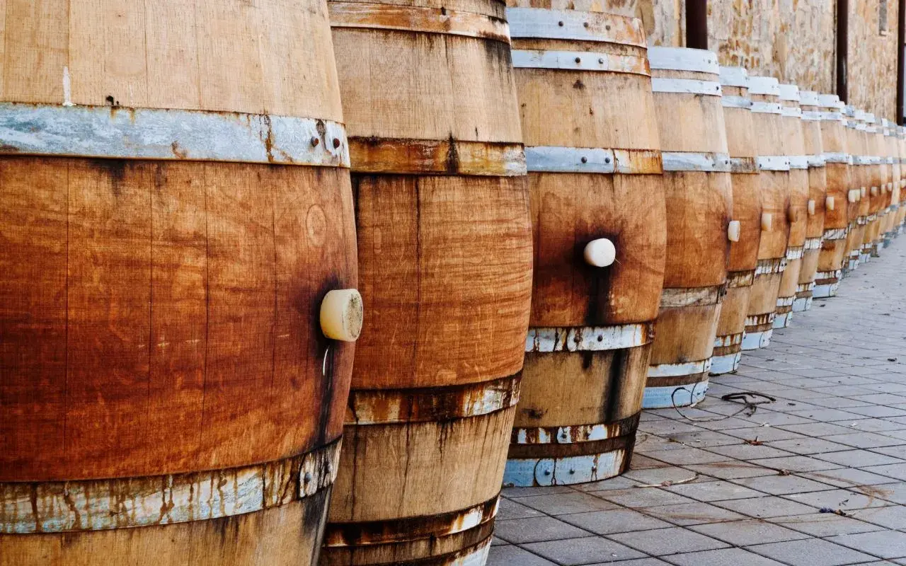 File di botti di legno in fila, pronte per la maturazione. La loro capacità barrique è fondamentale per il vino.