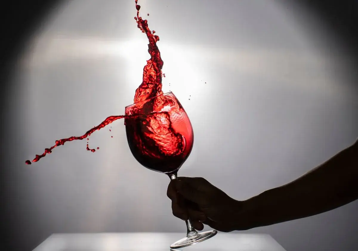 Un bicchiere di negramaro vino rosso in movimento, con schizzi vibranti che danzano nell'aria.