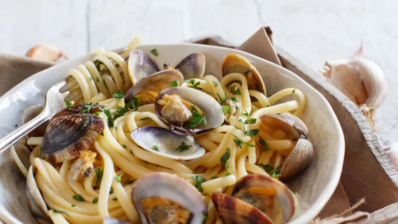 Un piatto invitante di spaghetti alle vongole, con pasta spessa e molluschi succulenti, guarnito con prezzemolo fresco.