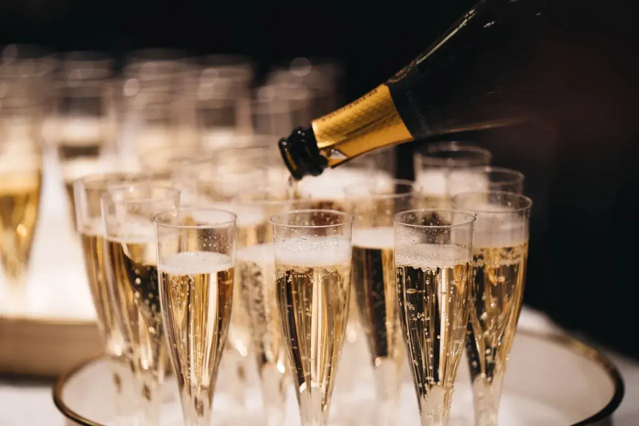 Bollicine dorate salgono in bicchieri di spumante, un brindisi che evoca il profumo millesimato significato di festa e celebrazione.