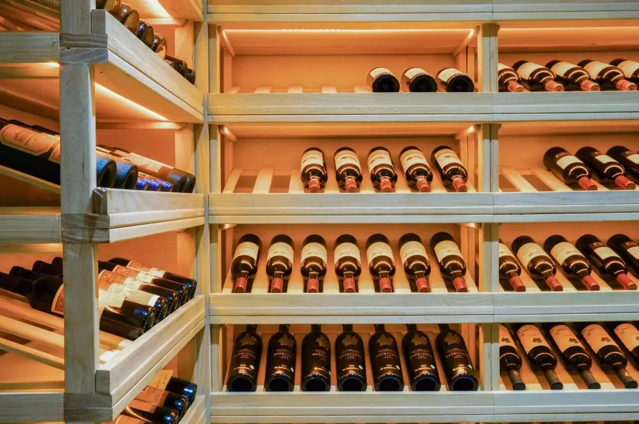 Cantina vini con bottiglie disposte su scaffali in legno, illuminazione soffusa che crea un'atmosfera perfetta per l'umidità ideale cantina vini.