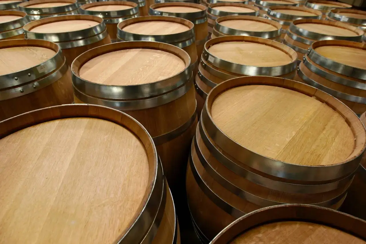 Fila di botti di legno, pronte per la stagionatura. La loro capacit&agrave; barrique &egrave; fondamentale per affinare vini e distillati.